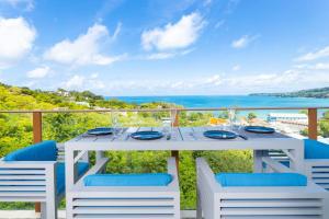 ein weißer Tisch und Stühle auf einem Balkon mit Blick auf das Meer in der Unterkunft Modern condo with full sea view, 4 min walk to Kamala beach in Kamala Beach