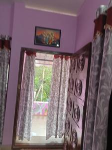 Una habitación con una ventana con cortinas y un espejo. en Ashabhavan, en Varkala