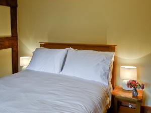 ein Schlafzimmer mit einem Bett mit weißer Bettwäsche und zwei Lampen in der Unterkunft Mill Cottage in Peterchurch