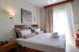 a bedroom with a large white bed with a window at Alkyonis Hotel in Nea Kalikratia