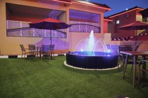 a fountain in the middle of a lawn with tables and umbrellas at بيوت العطلات الجوهرة سويت in Taif