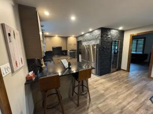 een keuken met een aanrecht met 2 stoelen en een koelkast bij Heated Indoor Pool - Maison au Bord du Lac in Rigaud +31 foto's