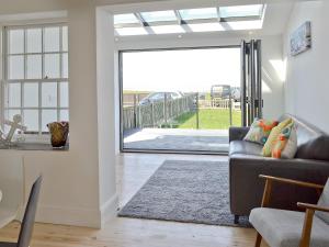 a living room with a couch and a sliding glass door at Coastguard Cottage in Chestfield