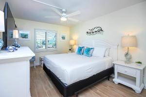 een slaapkamer met een wit bed met een plafondventilator bij Enchanting 2nd floor condo on Sanibel Island 4D2 in Sanibel +30 foto's