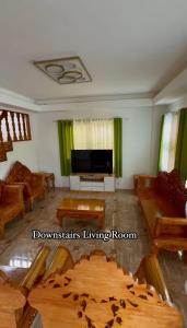 a living room with wooden furniture and a flat screen tv at The Meadow View House in Oobi