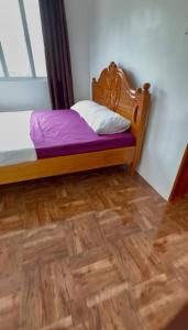 a bedroom with a bed with purple sheets and a wooden floor at The Meadow View House in Oobi