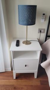 a nightstand with a lamp and a remote control on it at Little Apartment in Potenza