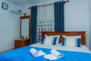 a bedroom with a blue bed with two white pillows at Shasha House Bentota in Hettiwatta