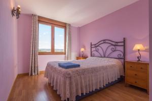 1 dormitorio con 1 cama con paredes de color púrpura y ventana en Casas Rurales La Niña A, en Villacorza