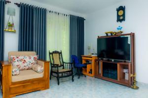a living room with a flat screen tv and chairs at Shasha House Bentota in Hettiwatta