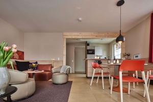 ein Wohnzimmer und eine Küche mit roten und weißen Stühlen in der Unterkunft Feriendorf Rerik in Rerik