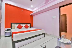 a bedroom with a bed with an orange wall at Magadh Imperial Guest House in Patna +9 photos