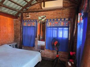 a bedroom with a bed and blue curtains and a fan at alojamiento Villa sarita in Posadas
