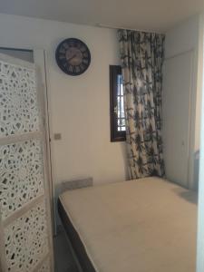 ein Schlafzimmer mit einem Bett und einer Uhr an der Wand in der Unterkunft chambre dans une residence à deux pas de la mer in Cannes