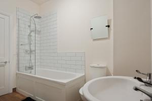 a white bathroom with a tub and a toilet at 3-Bed Home Perfect for Exploring Nottingham & Derby in Long Eaton