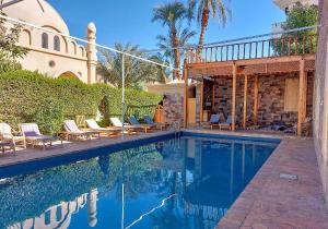 ein Swimmingpool mit Stühlen und ein Haus in der Unterkunft Embrace Guest House in Luxor