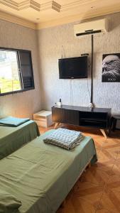 a room with two beds and a flat screen tv at Minas Hotel Uberlândia in Uberlândia