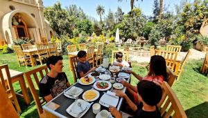 eine Gruppe von Menschen sitzt um einen Tisch herum und isst in der Unterkunft Embrace Guest House in Luxor