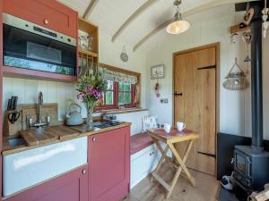 cocina con armarios rosas y mesa de madera en Bonnie's Shepherd Hut - Uk50228, en Nottingham
