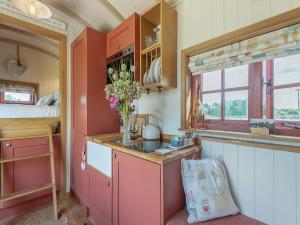 una cocina con armarios rojos y un jarrón de flores en Bonnie's Shepherd Hut - Uk50228, en Nottingham