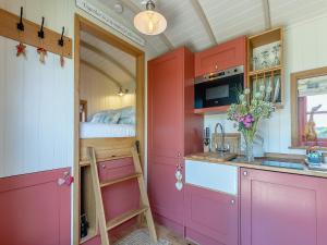 Una cocina con gabinetes rosas y una cama. en Bonnie's Shepherd Hut - Uk50228, en Nottingham 26 fotos más