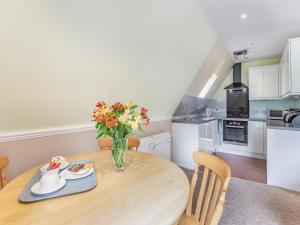 een keuken met een houten tafel en een vaas met bloemen bij Gorse Lodge - Uk7050 in Glenurguhart