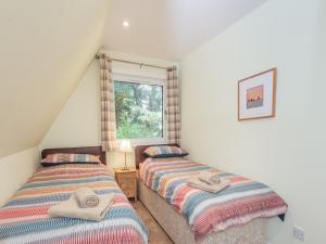 twee eenpersoonsbedden in een kamer met een raam bij Gorse Lodge - Uk7050 in Glenurguhart +9 foto's