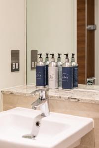 a bathroom sink with four bottles of soap at Stylish 2-Bed Penthouse Sleeps 6 Central Location in Belfast +104 photos