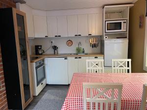a kitchen with white cabinets and a table and a microwave at Little Home in Kolari