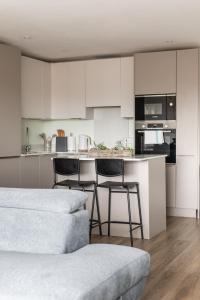 a kitchen with white cabinets and a counter with stools at Stylish 2-Bed Penthouse Sleeps 6 Central Location in Belfast