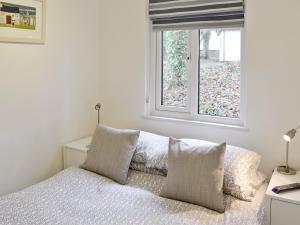 a bedroom with a bed with pillows and a window at Gracelands in Uny Lelant