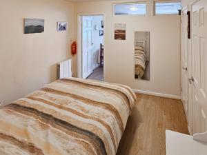 ein Schlafzimmer mit einem Bett in einem Zimmer mit Fenstern in der Unterkunft This 'N' That in Tintagel