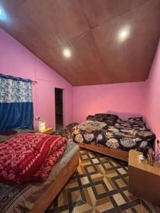 twee bedden in een kamer met roze muren bij Ghumakkad Homestay in Harsil