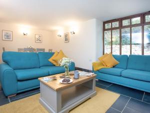 ein Wohnzimmer mit blauen Sofas und einem Tisch in der Unterkunft Uk45541-Old Stable Cottage in Sticklepath