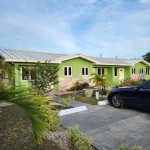 a green house with a car parked in front of it at Jubilee Gardens Freeport in Freeport