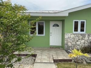 a green house with a white door at Jubilee Gardens Freeport in Freeport