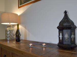 a table with a lamp and a bottle and a lantern at Ling Farm Cottage in Holmewood