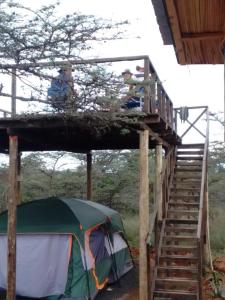 a tent with two people sitting on a deck at Ndege Mingi Bush Camp - Laikipia in Nanyuki
