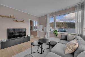ein Wohnzimmer mit Couch und großem Fenster in der Unterkunft Northstay - Tromsø Harbor Mountain View Apartment in Tromsø