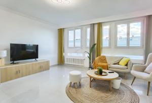 ein Wohnzimmer mit Fernseher, Couch und Tisch in der Unterkunft Modern 2-Bed Apt 80m2 with Elevator FREE Parking N19-25 in Paris
