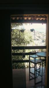 a table and chair on a balcony with a window at Pousada Mirante Pôr do Sol in Maricá