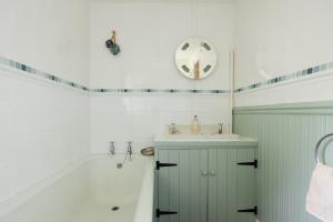a bathroom with a tub and a sink and a bath tub at Charming Upper Solva Cottage by Beaches and Harbour in Solva +29 photos