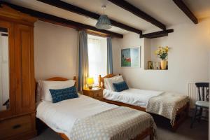 a bedroom with two beds and a table with a lamp at Charming Upper Solva Cottage by Beaches and Harbour in Solva