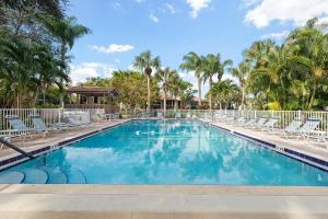 a large swimming pool with chairs and palm trees at Tranquil condo minutes from Venice Beach - Beach Bungalow in Nokomis