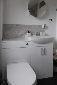 a white bathroom with a sink and a mirror at Comfortable Home Near Supermarket with Parking & Garden in Bullingham +26 photos