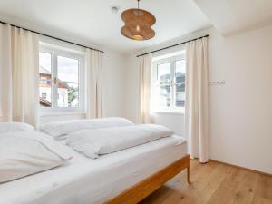 a white bedroom with two beds and two windows at Stöffler Haus Top 2 in Tamsweg