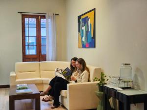 two women sitting on a couch reading a book at Hotel Vale Verde in Furnas