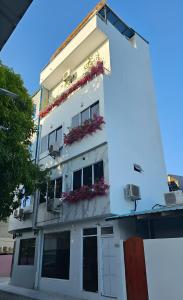 a white building with flower boxes on it at Naseema Hiya - Central Ukulhas Residences in Ukulhas
