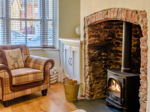 ein Wohnzimmer mit einem Kamin, einem Stuhl und einem Herd in der Unterkunft Hidden Winds Cottage in Guisborough