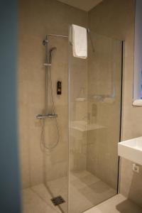 una ducha con puerta de cristal en un baño en qnorke Hotel, en Berlín